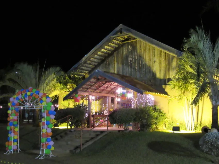 Fachada iluminada à noite com arco de balões na entrada