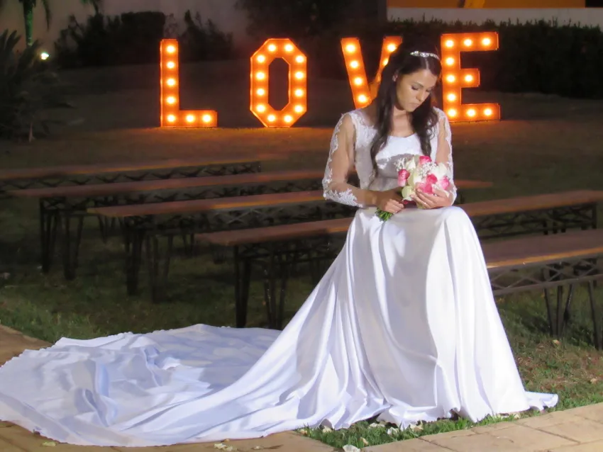 Noiva sentada diante do letreiro luminoso “LOVE”