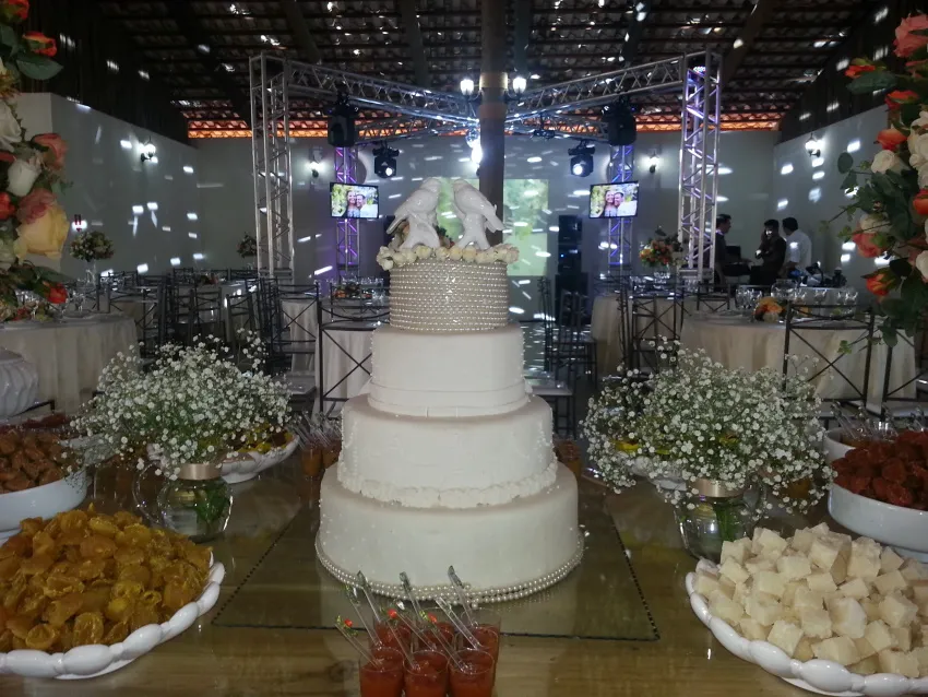 Bolo de casamento de quatro andares cercado por arranjos de flores
