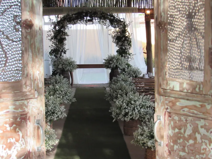 Arco de folhagem e flores brancas na entrada do salão