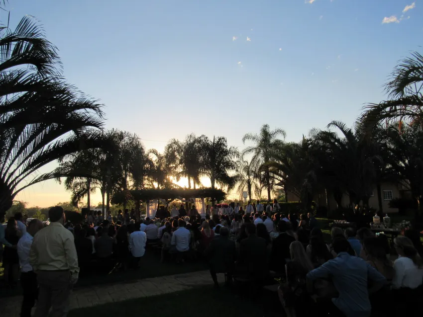 Cerimônia ao ar livre ao pôr do sol com convidados sentados