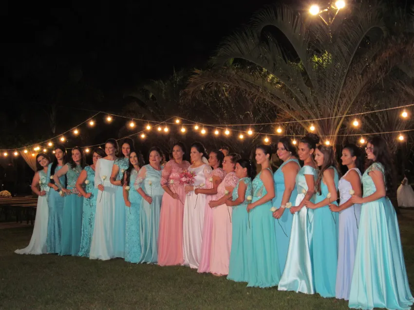 Convidadas em vestido longo sob varal de luzes à noite