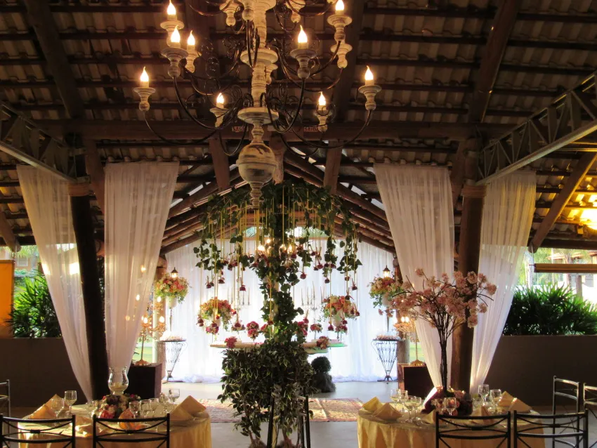 Salão com lustres, cortinas e arranjos suspensos de flores