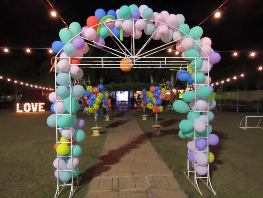 Arco de balões coloridos iluminado à noite no jardim