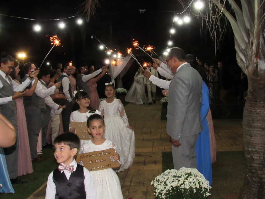 Convidados formando corredor com velas faíscas na saída dos noivos