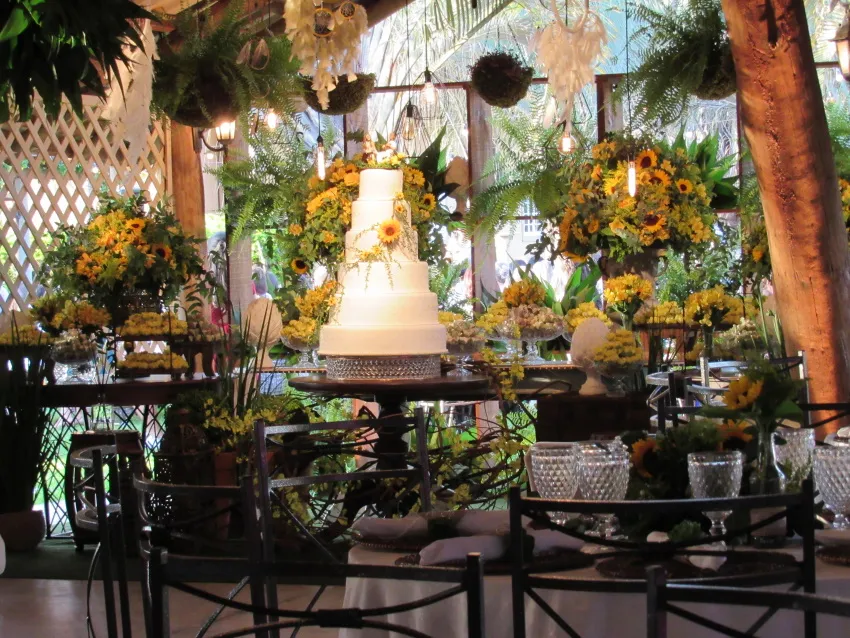 Mesa de bolo com arranjos de flores e frutas