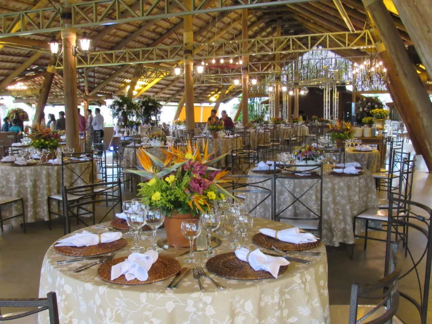Mesa posta com arranjo alto de flores, louça e taças