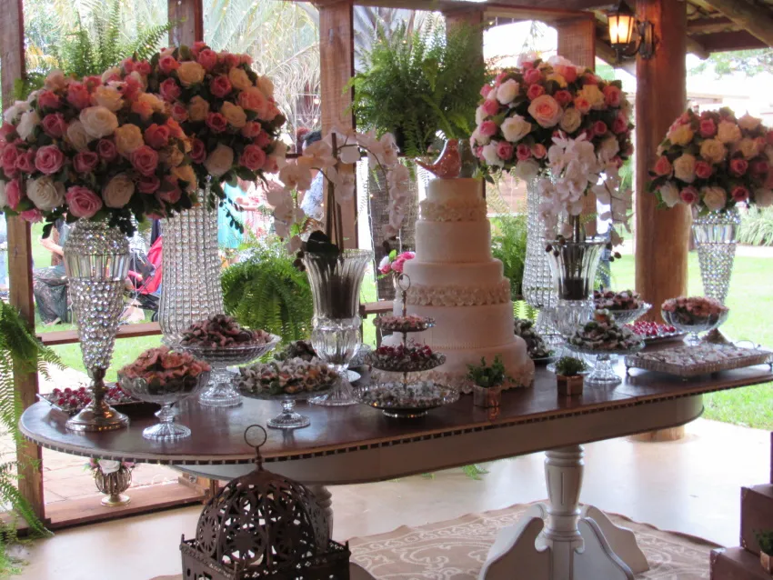 Mesa de doces com arranjos altos de rosas
