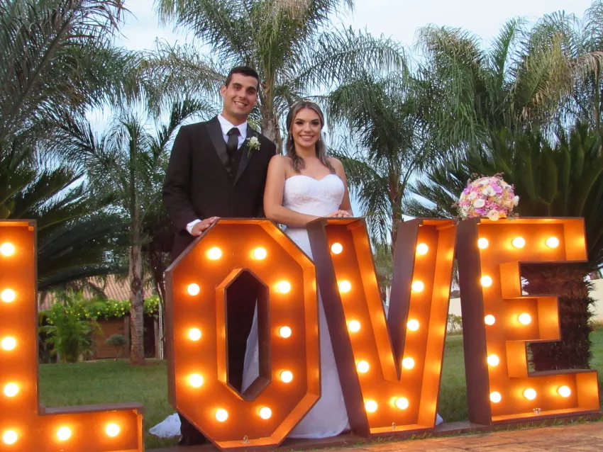 Casal de noivos diante do letreiro iluminado “LOVE”