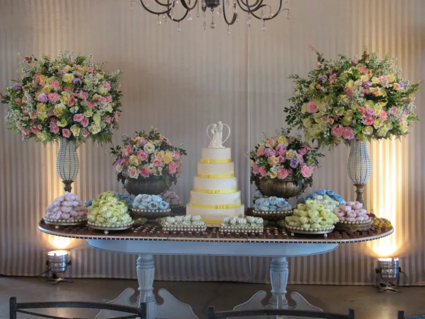 Mesa de bolo com arranjos de flores em tons de rosa