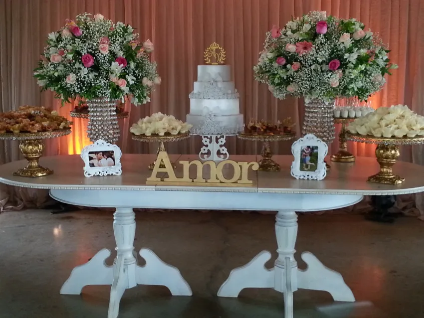 Mesa de bolo com letreiro “Amor” e arranjos de flores brancas