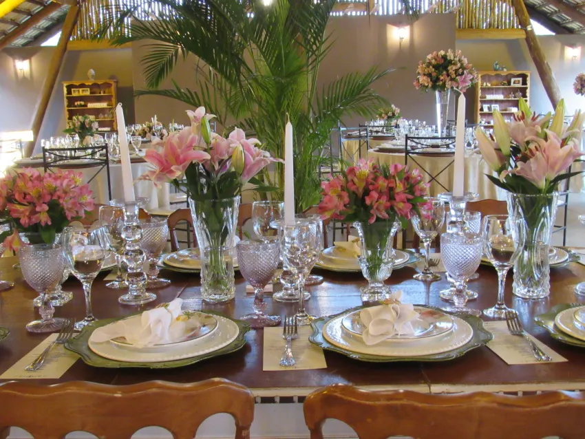 Mesa posta com arranjo de flores, taças de cristal e velas